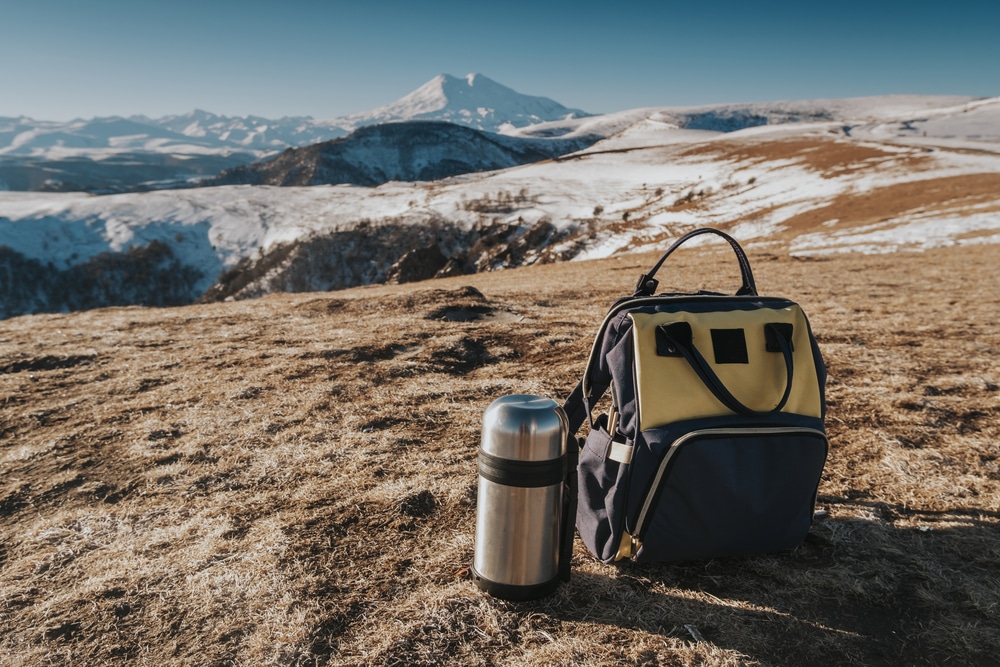 Thermos and backpack on montain top