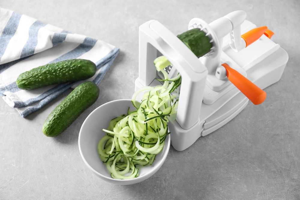Spiral vegetable slicer with cucumber spaghetti on table