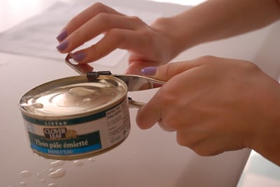 A pair of hands opening a canned food